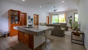 Een moderne keuken met een centraal eiland, houten kastjes en een zithoek met een bank en salontafel.