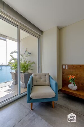 A modern room with a blue armchair, a wooden headboard, and a view of a pool. - ¡Luxurious TopSpot® with Amazing 21st Floor Views! (Cartagena)