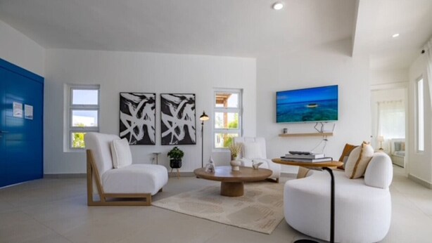 A modern living room with a sofa, armchairs, a coffee table, and artwork on the walls. - Sosua Ocean Village Villa 24 (Cabarete)