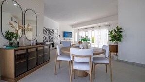 A modern dining area with a round table, white chairs, and a wooden cabinet. - Sosua Ocean Village Villa 24 (Cabarete)