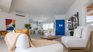 A modern living room with white sofas, a coffee table, and a kitchen in the background. - Sosua Ocean Village Villa 24 (Cabarete)