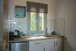 Una cocina con lavavajillas incorporado, cafetera y ventana con vistas a zonas verdes.