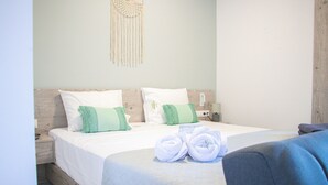 A neatly made bed with white and green pillows, a wooden headboard, and a macrame wall hanging. - House of Harmony Suites | Luca (Agia Pelagia)