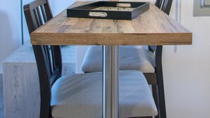 Een eettafel met een dienblad, stoelen en een potplant.