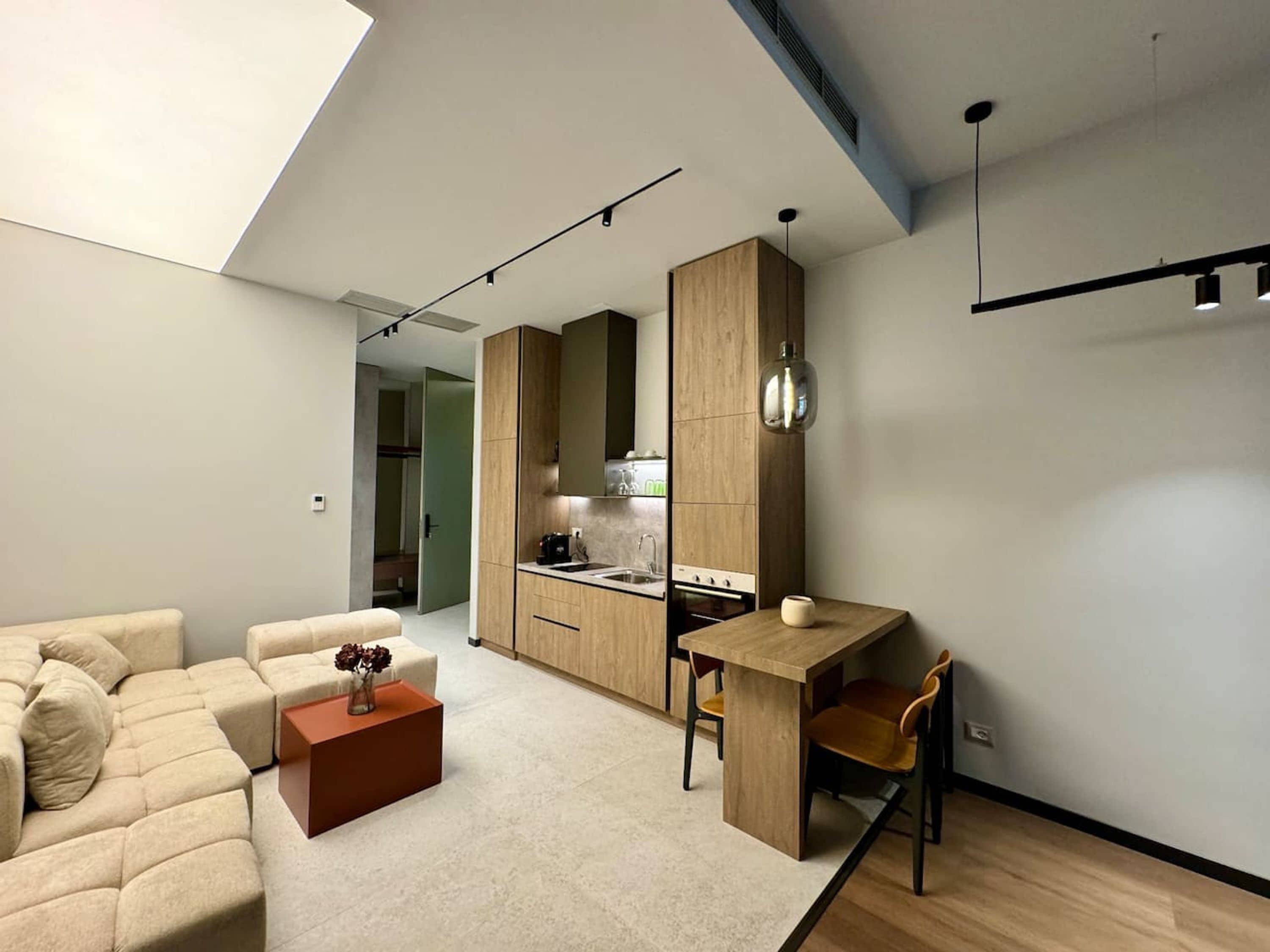 A modern living room with a sofa, a coffee table, and a dining area with a table and chairs.