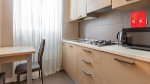A compact kitchen with a microwave, toaster, and kettle. There is a dining table with a chair, and a red welcome sign on the wall. - Desenzano Suites - Artemisia by Wonderful Italy (Desenzano del Garda)