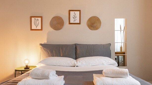 A neatly made bed with two pillows, a bedside table with a lamp, and three framed botanical prints on the wall. - Desenzano Suites - Artemisia by Wonderful Italy (Desenzano del Garda)