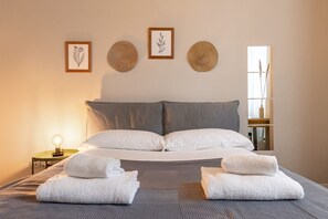 A neatly made bed with two pillows, a bedside table with a lamp, and three framed botanical prints on the wall. - Desenzano Suites - Artemisia by Wonderful Italy (Desenzano del Garda)