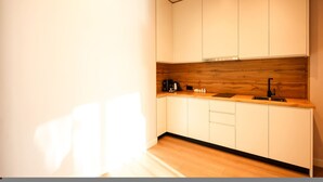Eine moderne Küche mit weißen Schränken, einer Holzrückwand und einem schwarzen Wasserhahn.