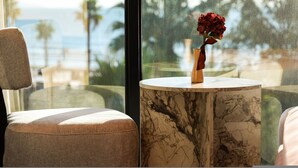 Blick aus einem Fenster mit einem Marmortisch und einer Vase mit roten Blumen.
