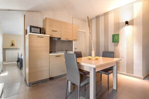 A modern kitchen with wooden cabinets, a microwave, and a dining area with a table and chairs. - Desenzano Suites - Tiglio by Wonderful Italy (Desenzano del Garda)
