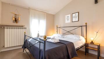 Ein Schlafzimmer mit Bett, Heizkörper, Nachttisch mit Lampe und Fenster mit Vorhängen.