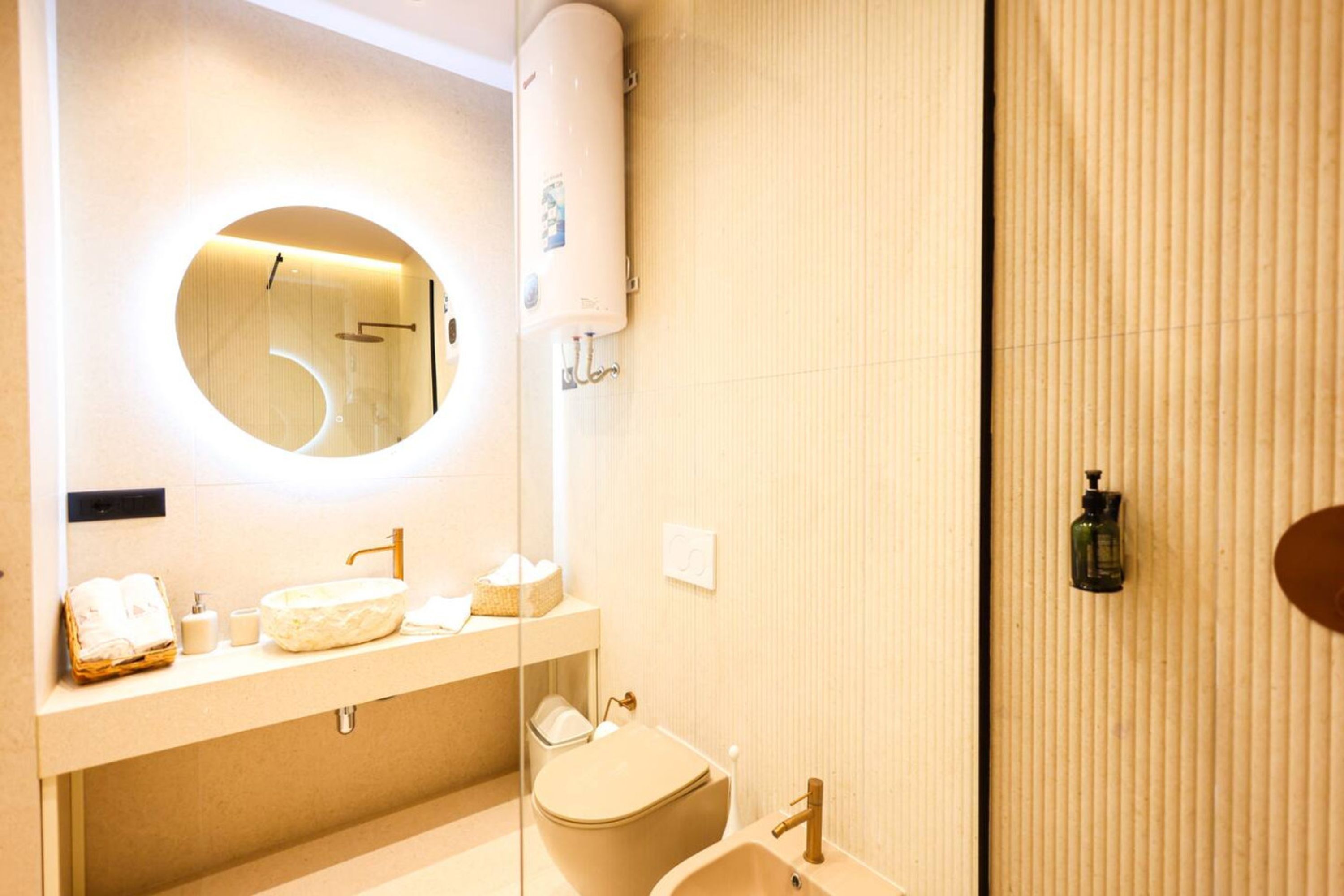 A modern bathroom with a round mirror, a sink, a toilet, and a towel rack.