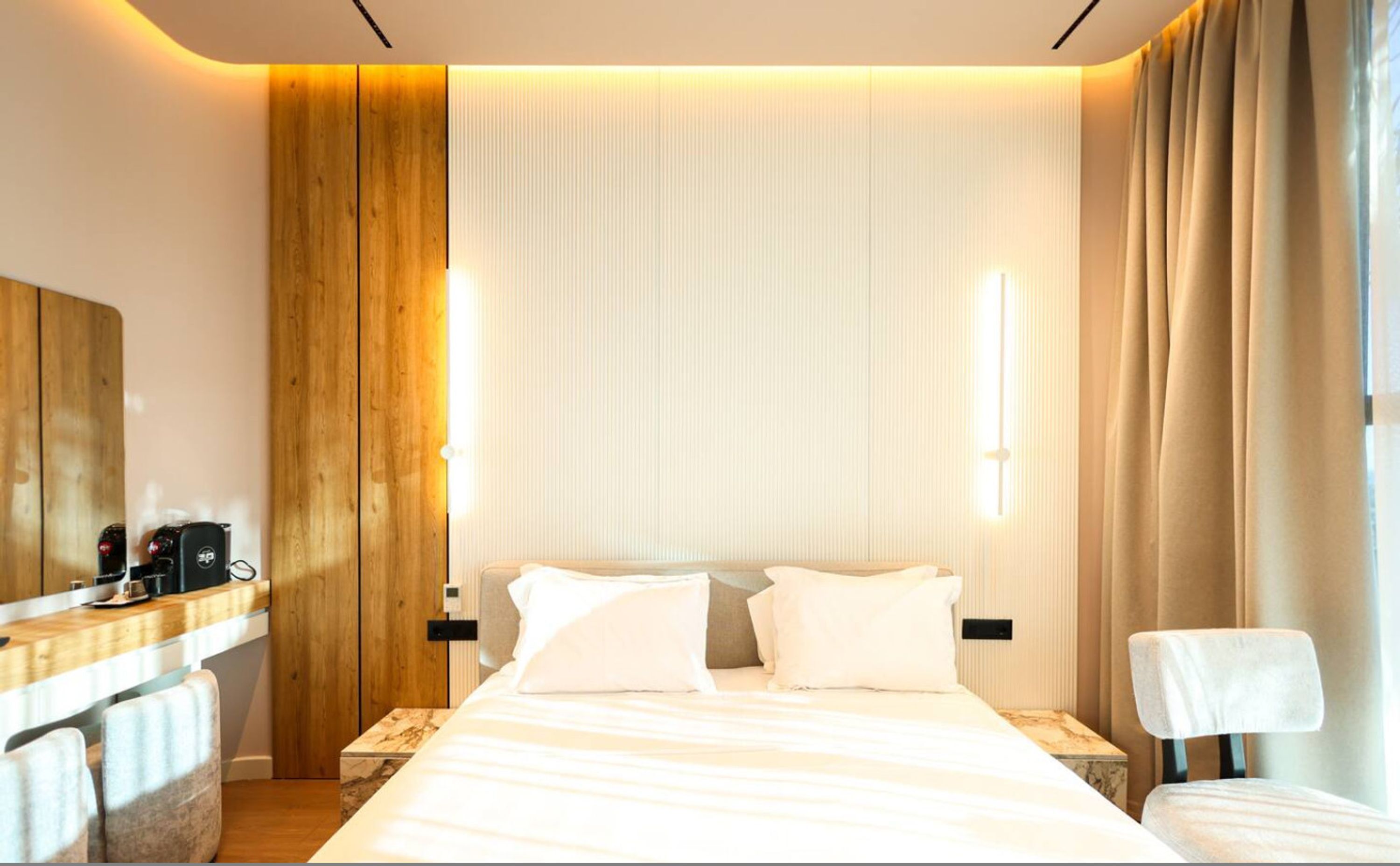 Une chambre d’hôtel avec un grand lit, des tables de chevet, un mur recouvert de panneaux en bois et une fenêtre avec des rideaux.