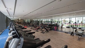 Ein modernes Fitnessstudio mit Cardiogeräten, Kraftmaschinen und einem großen Fenster mit Blick ins Freie.