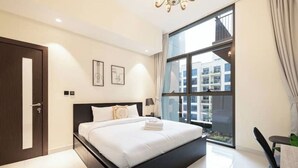 Ein modernes Hotelzimmer mit einem großen Bett, einem Fenster mit Blick auf die Stadt und einer Tür.