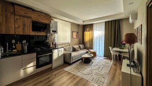 A modern kitchen with wooden cabinets, a built-in oven, and a black countertop. - Smartly Designed Cozy Central 1BR Apartment (Antalya)