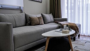 A modern living room with a grey sofa, a white coffee table, and a small side table. - Smartly Designed Cozy Central 1BR Apartment (Antalya)