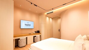 Ein modernes Hotelzimmer mit Bett, Schreibtisch und Fernseher, der die Grandstay Collection zeigt.
