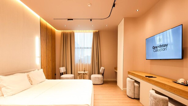 Ein modernes Hotelzimmer mit Bett, Schreibtisch, Fernseher und Sitzecke.