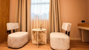 Ein Zimmer mit zwei runden Hocker, einem kleinen runden Tisch mit Marmoroptik und einem Holzkopfende.