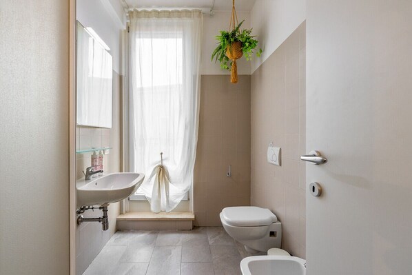 Un baño con lavamanos, inodoro y zona de ducha.