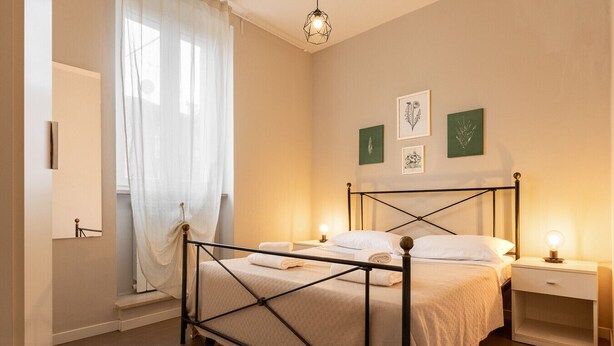 Ein ordentlich eingerichtetes Schlafzimmer mit einem Bett, Nachttischen und Kunstwerken an der Wand.