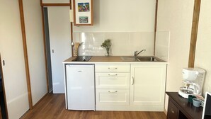 A compact kitchen with a refrigerator, sink, and coffee maker.