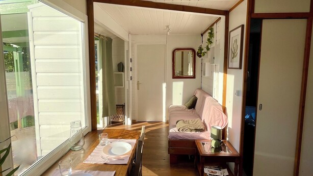 A dining area with a wooden table set for four, a sofa, and a mirror on the wall.