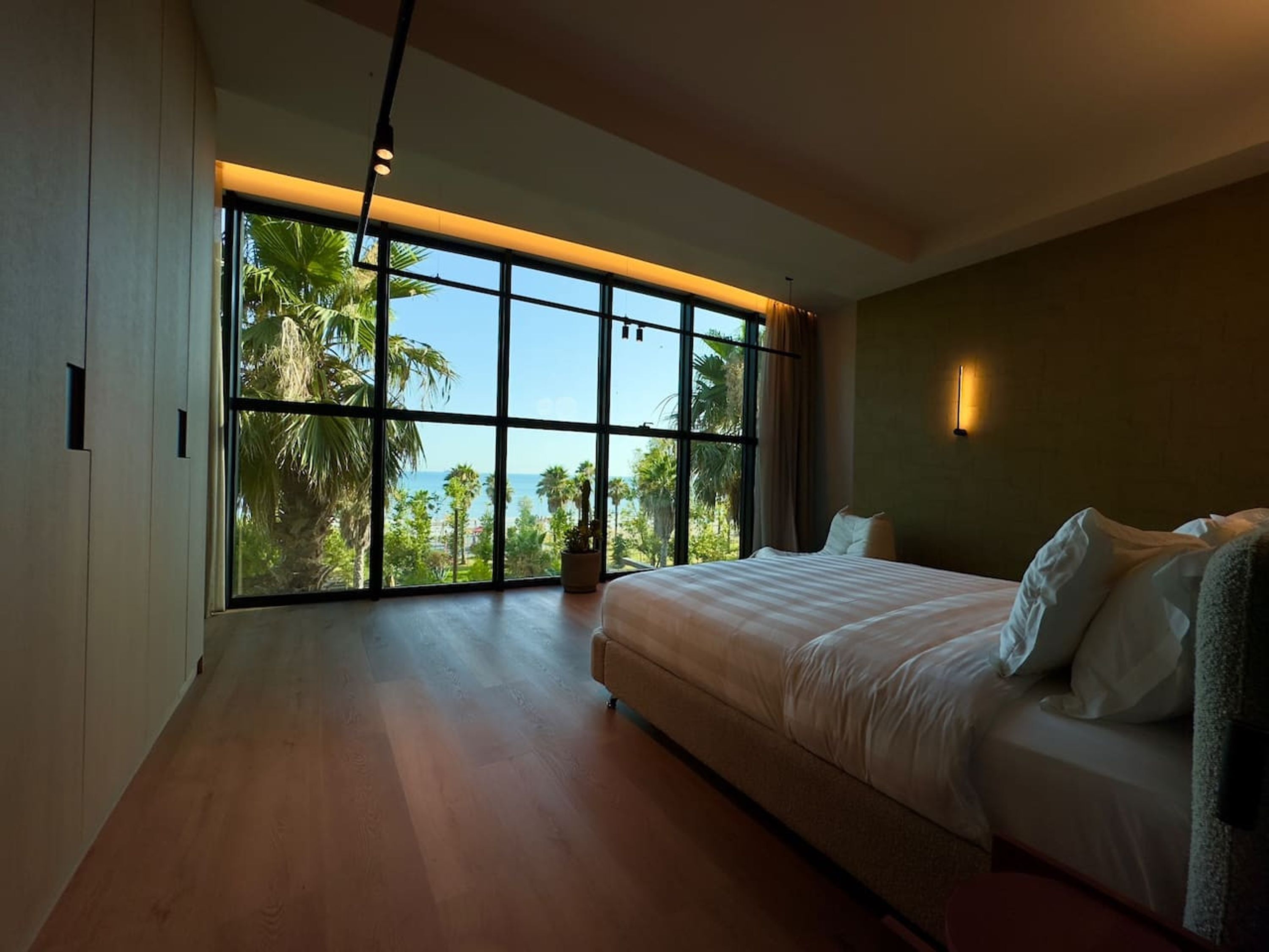 A modern bedroom with a large window, a bed, and a potted plant.
