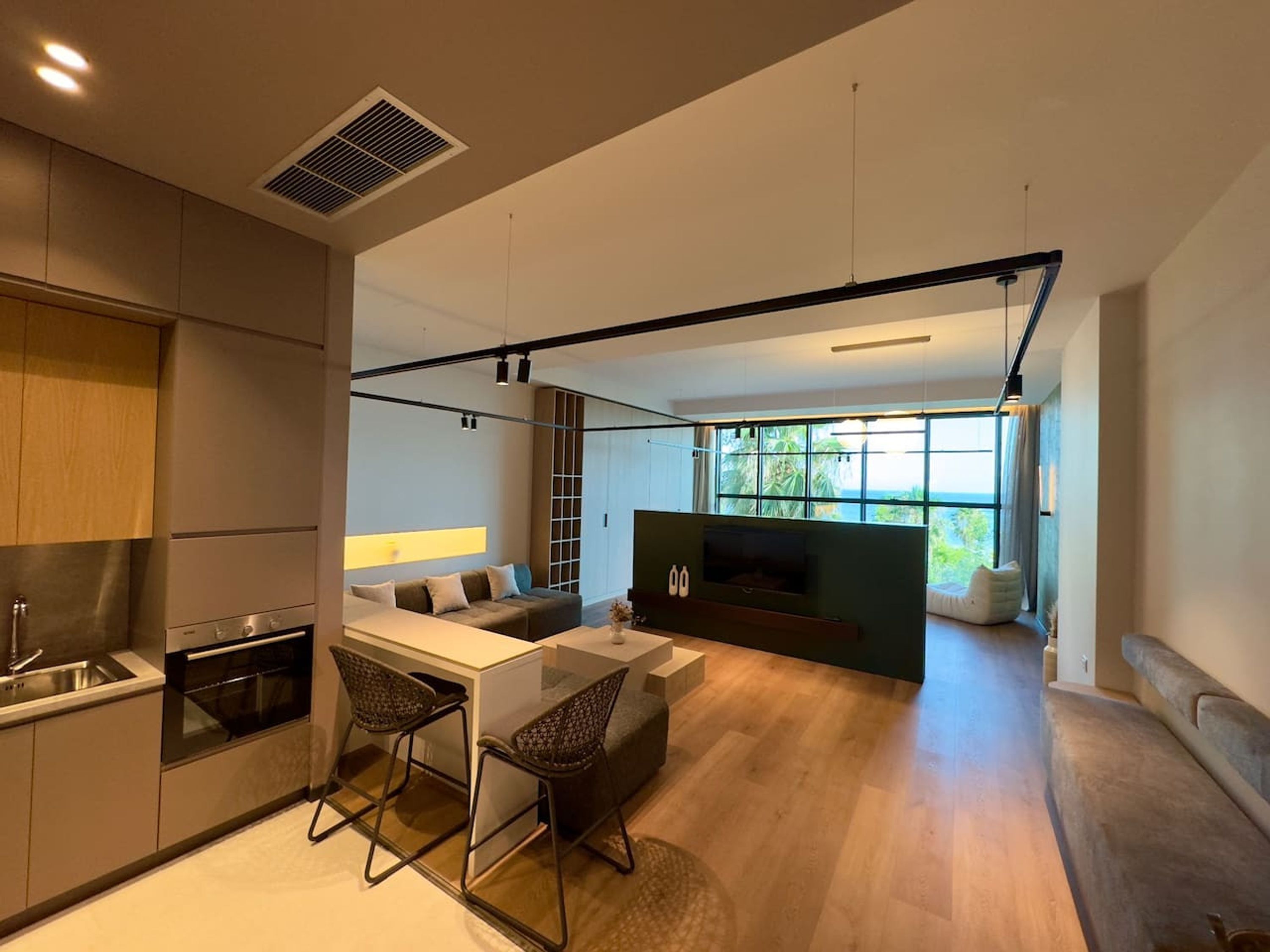 A modern kitchen with a dining area, built-in appliances, and a large window offering a view.