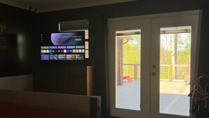 Un dormitorio con cama, ventilador de techo, televisor en la pared y puerta corrediza de vidrio que da a un espacio al aire libre.