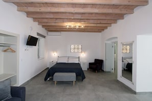 Ein Schlafzimmer mit Bett, Nachttischen, einem Sessel, einem Fernseher und einem Spiegel.