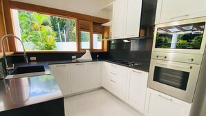 Una cocina moderna con armarios blancos, encimera negra y estufa y horno de acero inoxidable.