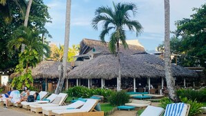Un resort con estructuras de techo de paja, asientos al aire libre y sillones de descanso.