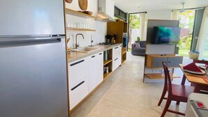 A modern kitchen with a built-in oven, a sink, and a dining area with a TV and table. - Private Pool Villa | Parking | Washer (Las Terrenas)