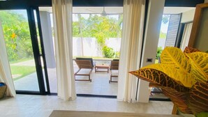 A modern room with a sliding glass door leading to an outdoor area with a table and chairs. - Private Pool Villa | Parking | Washer (Las Terrenas)