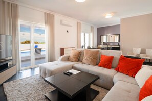 A modern living room with a sofa, a coffee table, a TV, and a balcony with a view. - Novo Amanha in Deerfield Beach (Quelfes)