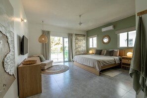 A bedroom with a bed, a sofa, a TV, and a large window. - 3 Bedroom Beachfront Apartment (Las Terrenas)