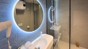 Ein modernes Badezimmer mit rundem Spiegel, einer Duschkabine und einem weißen Waschbecken.