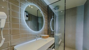 Een moderne badkamer met een grote spiegel, een witte wastafel en een douchecabine van glas.