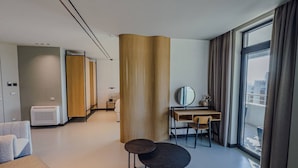 Een moderne hotelkamer met een groot raam, een bureau, een stoel en een bank.