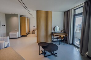 Ein modernes Hotelzimmer mit großem Fenster, einem Schreibtisch, einem Stuhl und einer Couch.