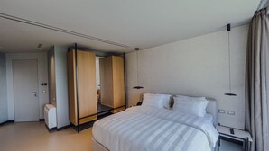 Een moderne hotelkamer met een groot bed, een garderobe, een nachtkastje en een afstandsbediening.