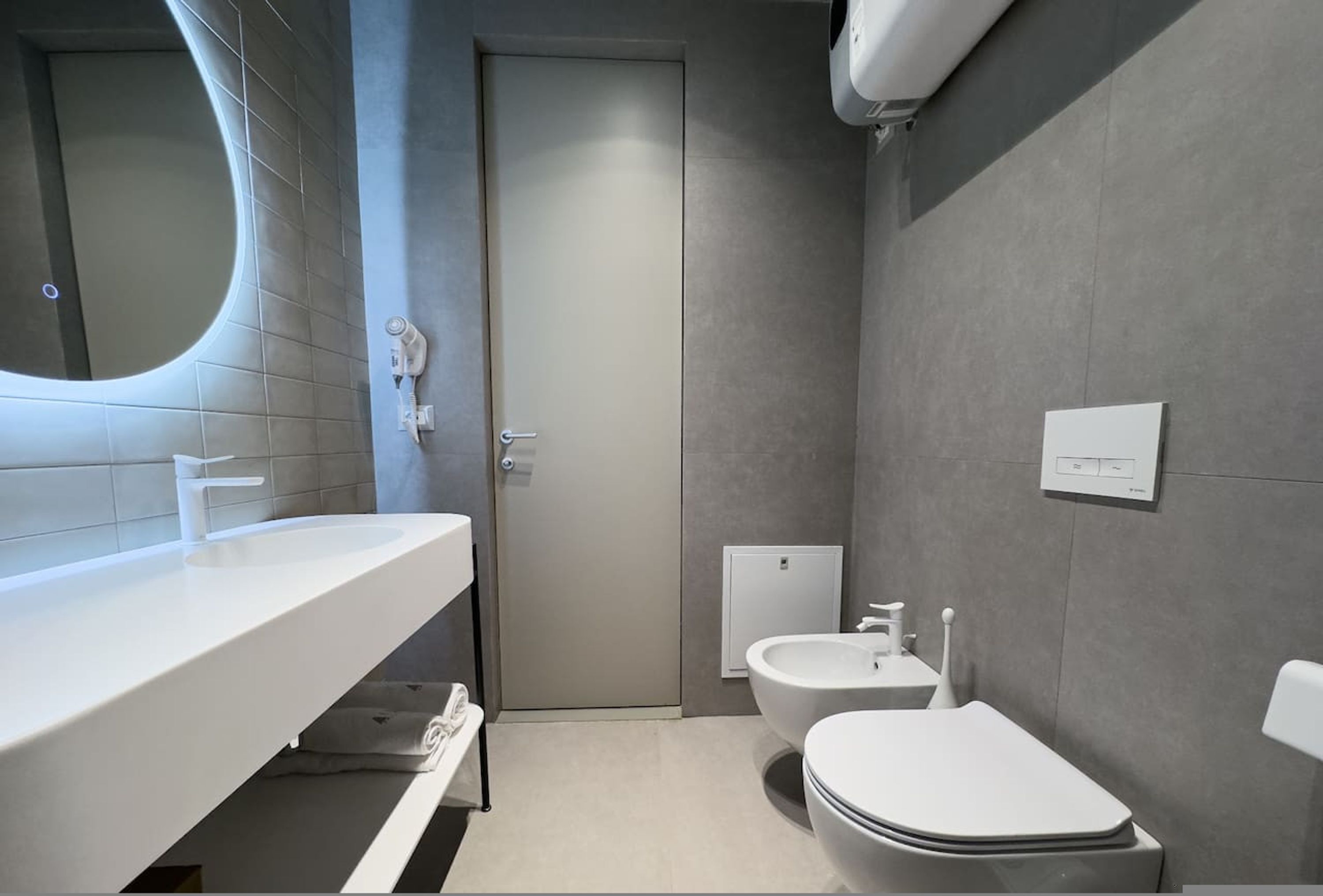 A modern bathroom with a white sink, a toilet, and a bidet.