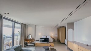 Een moderne hotelkamer met een bank, een bureau, een televisie en een bed.