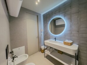 Ein modernes Badezimmer mit einem weißen Waschbecken, einem runden Spiegel und einer Badewanne.
