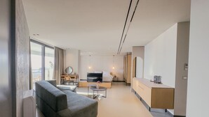 Een moderne hotelkamer met een bank, een klein rond tafeltje, een televisie en een houten kast.