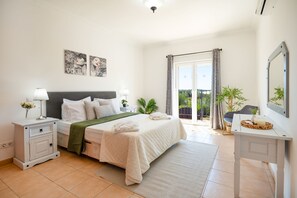 Ein Schlafzimmer mit Bett, Nachttischen, Vorhängen an einem Fenster und einem Balkon, sowie einer Topfpflanze.