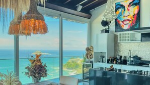 A modern kitchen with a large island, a dining area with a view of the ocean, and a ceiling with hanging lights. - Stunning mansion in Joatinga, Rio de Janeiro. (Rio de Janeiro)